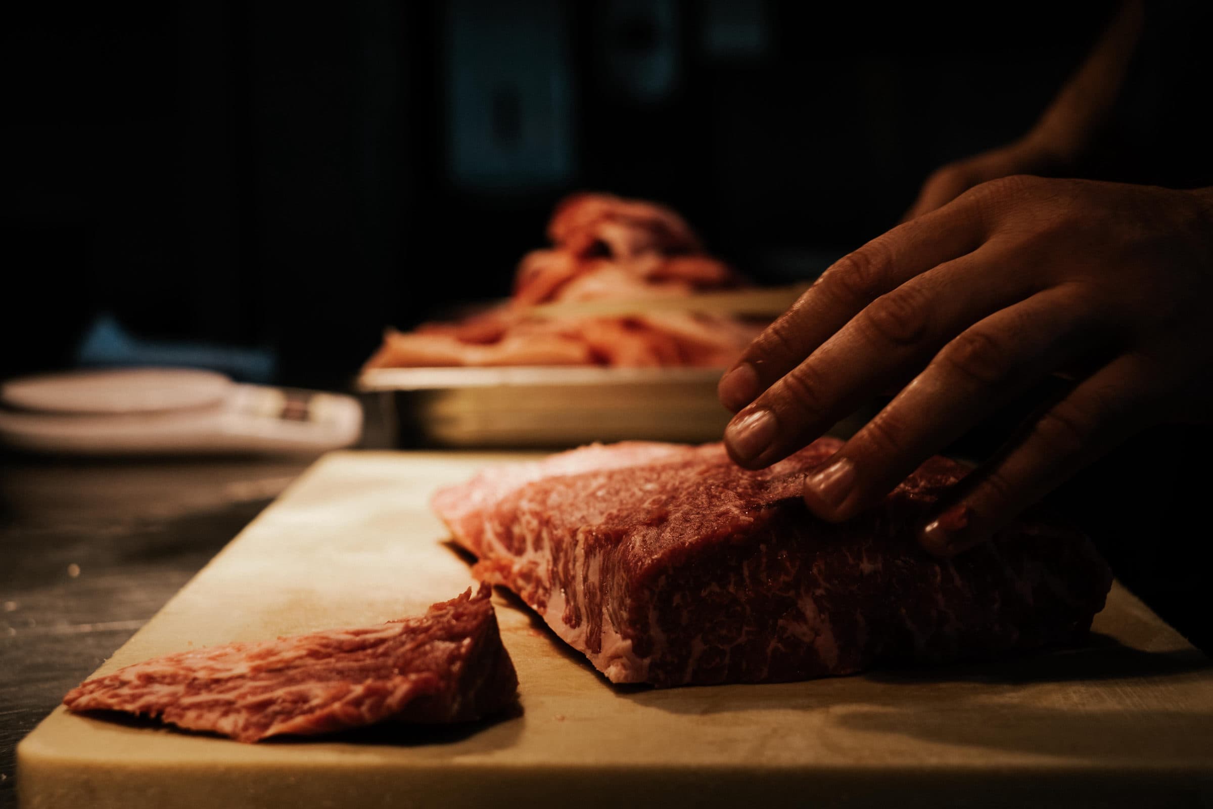 Hands cutting meat on a wooden block